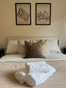 Una cama con toallas en ella con tres cuadros en la pared en Bungalow on the Hill, en Exeter