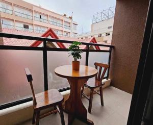 バギオにあるCondotel Near SM Baguio, Cathedral & Session Rd by Le Chateau Baguioのバルコニー(テーブル、椅子2脚、鉢植えの植物付)