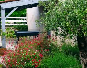 a bench in a garden with red flowers at Les gites de Pétrocoriis - Boulazac Périgueux in Boulazac