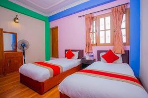 two beds in a room with blue and green walls at Hotel Om in Baudhatinchule