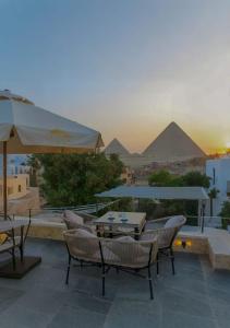 a patio with tables and chairs with pyramids in the background at Lavista pyramids view hotel in Cairo +49 photos
