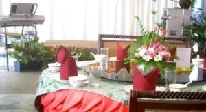 a table with flowers and bowls on top of it at Vasu Hotel Mahasarakham in Maha Sarakham