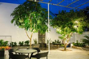 a patio with a table and chairs and trees at Villa De Doc Let Homestay in Nha Trang