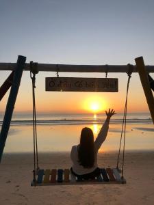 a woman sitting on a swing on the beach watching the sunset at Villa De Doc Let Homestay in Nha Trang