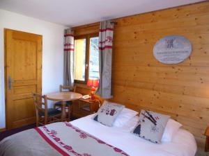 a bedroom with a bed and a wooden wall at Epicéa Lodge Hôtel in Pralognan-la-Vanoise