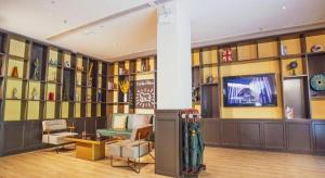 a lobby with a television and a couch and chairs at City Comfort Premier Hotel Xiaogan Anlu Railway Station Dongda Times Square in Xiaogan