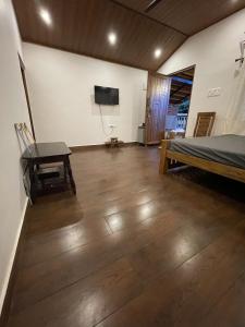 a bedroom with a bed and a desk and a television at Naad Alaya Estate Stay in Siddapur