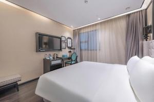 a hotel room with a large bed and a television at Xana Hotelle Zhuhai Gongbei Port in Zhuhai