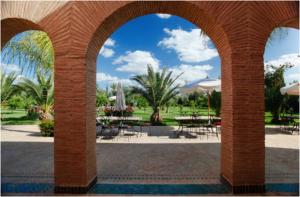 un arco con mesas y sillas en un parque en Villa Dar Mya Palmiers, en Marrakech