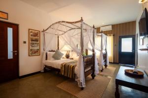 a bedroom with a four poster bed with a canopy at Riverdale Bungalow - Film Location For 'Bridge On The River Kwai' in Kandy
