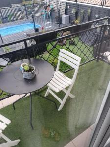 einen Tisch und Stühle auf einem Balkon mit Pool in der Unterkunft Pleasant little cottage in Pont-sur-Yonne