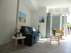 Una sala de estar con un sofá azul y dos mesas. en Stunning apartment in Schoorl, North Hollandâ you can bike to the beach, en Schoorl