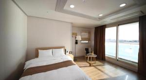a bedroom with a bed and a large window at Hotel Aroha Jeju in Seogwipo +168 photos