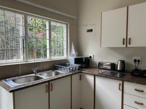 a kitchen with a sink and two windows at Private Garden Studio Cottage with BBQ 10 min walk to Pennington Beach in Pennington