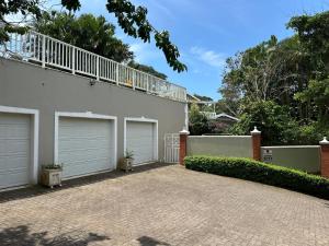 ein Haus mit zwei Garagentüren und einer Terrasse in der Unterkunft Douglas Cottage in Pennington