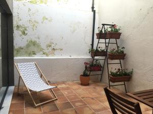 a patio with a chair and potted plants on a wall at Casa dos Pátios in Aveiro