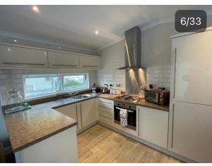 a kitchen with white cabinets and a white refrigerator at Quince on Oakdene country Park in Ringwood