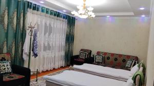 a living room with two couches and a chandelier at Asem Guest House in Kazarman