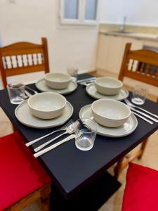 a black table with white plates and silverware on it at Soho Heaven - Cloud & Relaxation Atmosphere 2 Bedrooms in Essaouira