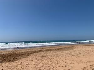 a beach with people walking on the sand and the ocean at Perfect stay in Agadir