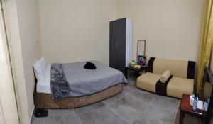 a small bedroom with a bed and a chair at Entire studio apartment near Al ain mall in Al Ain