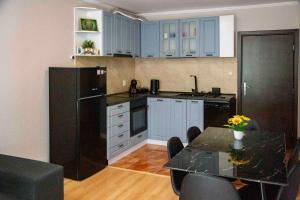 a kitchen with a table and a black refrigerator at Forest Dream Apartment - Elit Pamporovo in Pamporovo