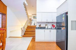 a kitchen with white cabinets and a black refrigerator at White Sand Pool Villa Pattaya in Jomtien Beach