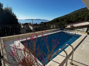 a swimming pool with some pink flowers in it at Aura Adriatica Olive - Luxury Apartment, private pool, sea view, parking in Lovran