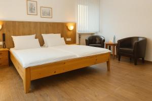 a bedroom with a bed with two chairs and a table at Hotel Orthwein -kostenfreie Parkplätze- in Cölbe