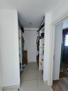 a walk in closet with white walls at F3 entier de standing tout équipé vue mer, piscine partagée et parking souterrain in Noumea