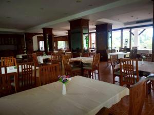 a dining room with tables and chairs and a vase of flowers at Lifeup care and hotel in Ban Mai
