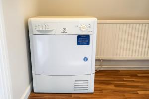 a small refrigerator in a room next to a wall at Modern 3-Bedroom Home with Free Parking for Family, Contractors and Tourists! in Sittingbourne