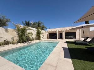 a swimming pool next to a house with an umbrella at Casa Isabel in Chipiona