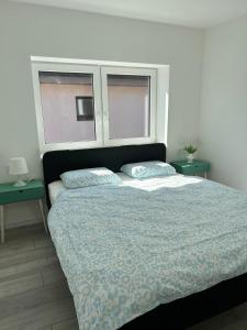 a bedroom with a large bed with two windows at Apartman Bojnice Kúpele in Bojnice