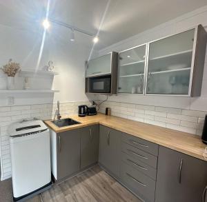 a kitchen with a counter with a sink and a microwave at Across The Dunes, Papamoa in Papamoa