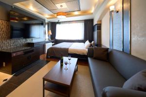 una camera d'albergo con divano, letto e TV di ホテル フェスタ 葉山 a Hayama