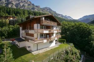 ein Haus auf einem Hügel mit Bergen im Hintergrund in der Unterkunft Apartments Weid in Leukerbad