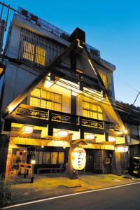 un bâtiment avec une enseigne sur la façade dans l'établissement 民話の宿荒澤屋旅館, à Okutama
