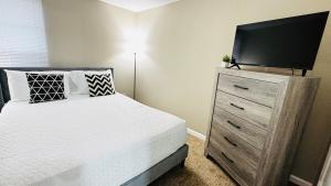 a bedroom with a bed and a dresser with a flat screen tv at Lavish Escape in Charlotte