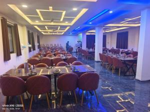 a banquet hall with tables and chairs and a man in the background at Hotel Nandi Resort in Jiwājīnagar