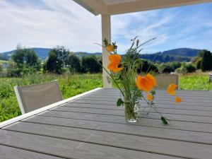 un vase avec des fleurs orange assis sur une table dans l'établissement Modern Vosges Getaway, à Laveline