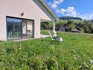 deux chaises assises dans l'herbe à côté d'une maison dans l'établissement Modern Vosges Getaway, à Laveline