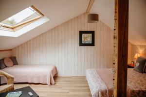 a attic bedroom with two beds and a window at Le Clos De La Roche in Goven