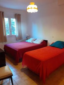 a bedroom with two beds with red sheets at Appartement T2 Alistro San Giuliano Corse in San-Giuliano