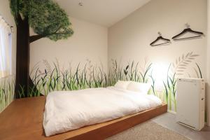a bedroom with a bed with a tree painted on the wall at E10Hostel in Tokyo