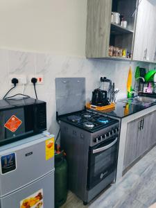 eine Küche mit Herd und Mikrowelle in der Unterkunft Staycation with Ryn in Ruaka