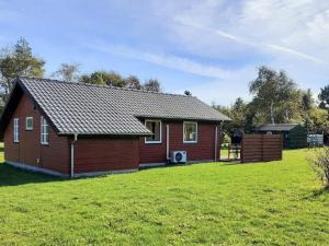 a small house in a field with a grass yard at 6 person holiday home in Nibe in Nibe