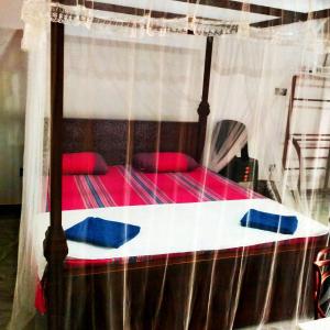 a canopy bed with red and blue pillows on it at White Angel in Mirissa