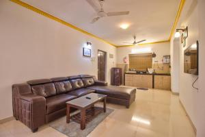 a living room with a brown leather couch and a table at Amazing Pool View 2BHK Candolim Goa Apartment in Candolim