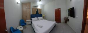 a small bedroom with a bed and two blue chairs at Seaview Residency in Karachi